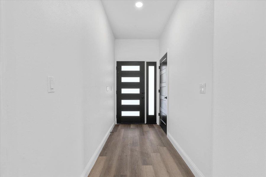 Smooth wood floors guide the way through a clean, modern entryway framed by crisp white walls. Smooth wood floors guide the way through a clean, modern entryway framed by crisp white walls.
