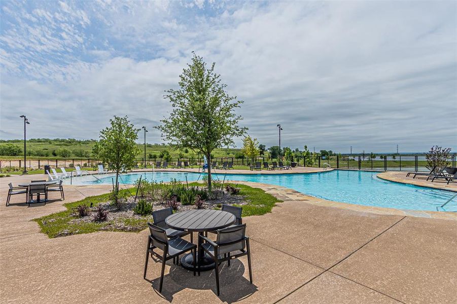 Expansive community pool with a freeform design, featuring a surrounding concrete deck and integrated lounge areas