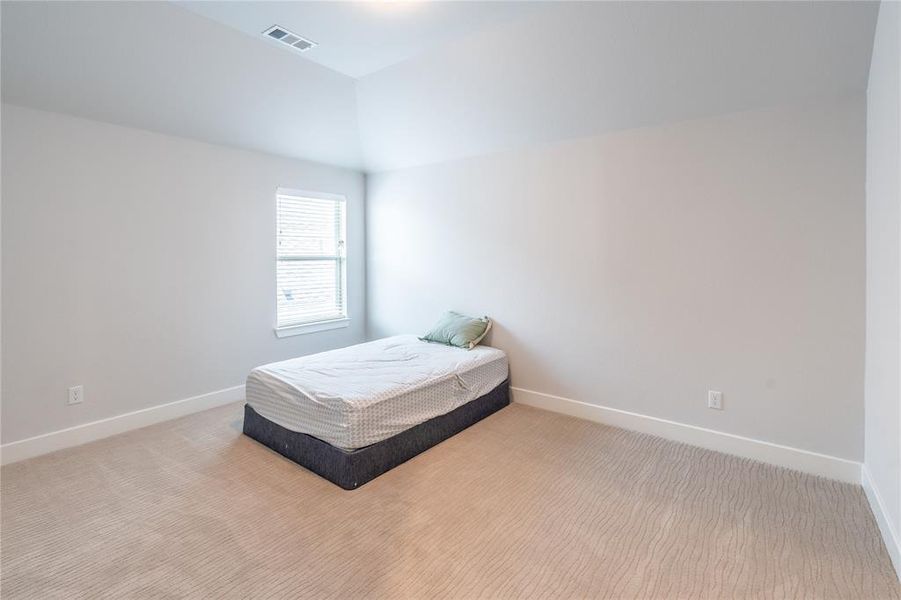 Carpeted bedroom featuring a desk and vaulted ceiling