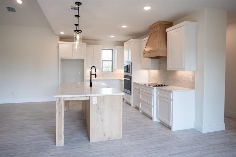 Kitchen with backsplash, decorative light fixtures, a breakfast bar, recessed lighting, and a kitchen island with sink Kitchen with backsplash, decorative light fixtures, a breakfast bar, recessed lighting, and a kitchen island with sink
