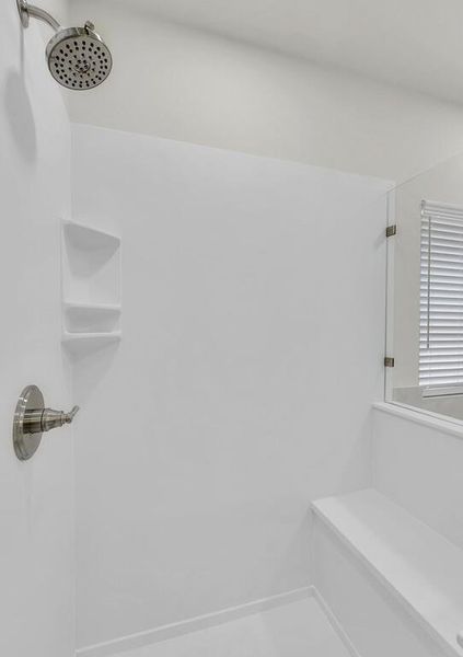 Full bath featuring a tile shower and baseboards