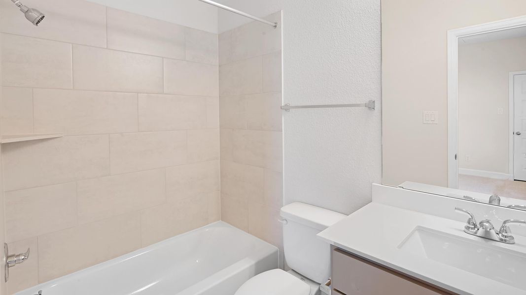Bathroom featuring bathing tub / shower combination, vanity, and a textured wall