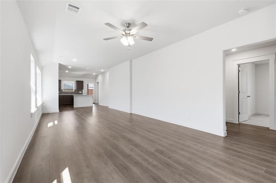Unfurnished living room featuring ceiling fan, dark wood-type flooring, and recessed lighting