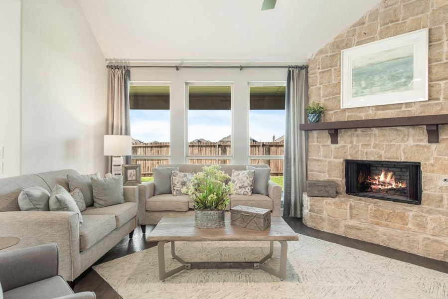 Living room with gray sofas, wood coffee table, and floor-to-ceiling stone fireplace with wood mantel