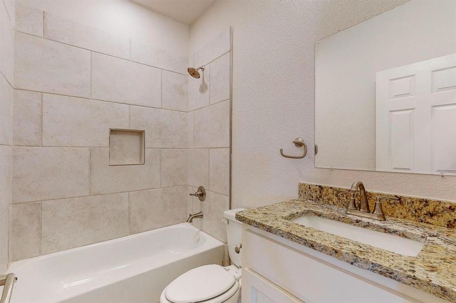 Full bathroom with vanity, tiled shower / bath combo, and toilet