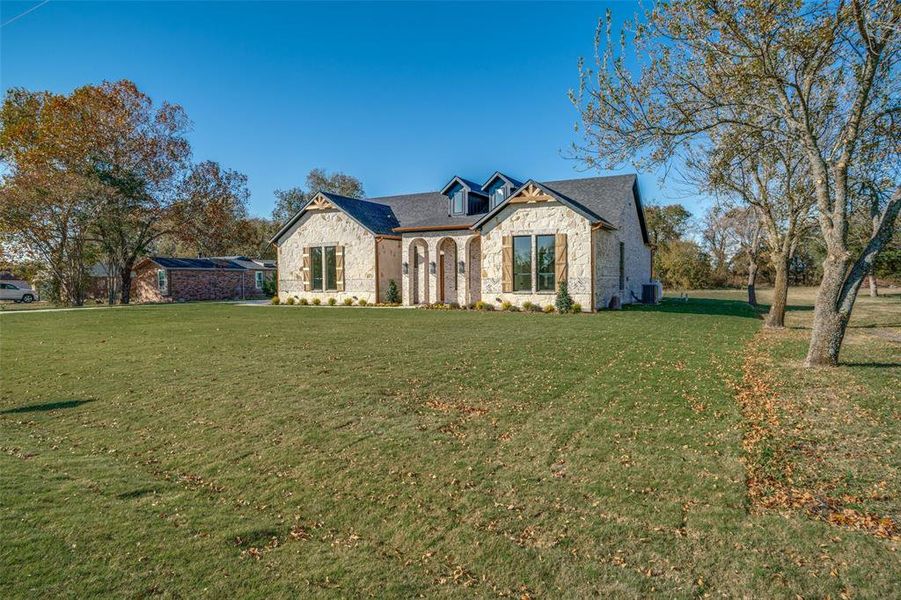 French provincial home featuring stone siding, a front yard, and brick siding French provincial home featuring stone siding, a front yard, and brick siding