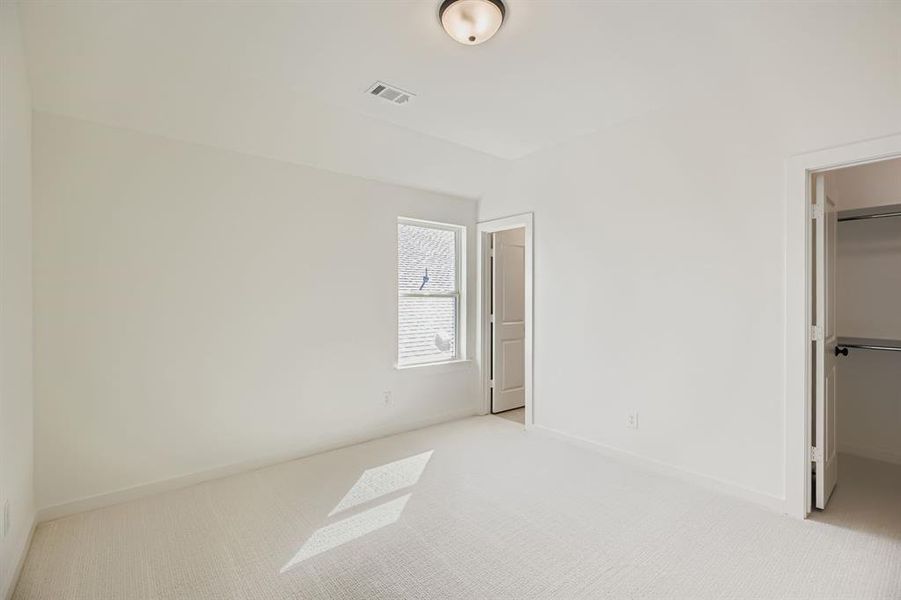 Unfurnished bedroom featuring a walk in closet and carpet flooring Unfurnished bedroom featuring a walk in closet and carpet flooring