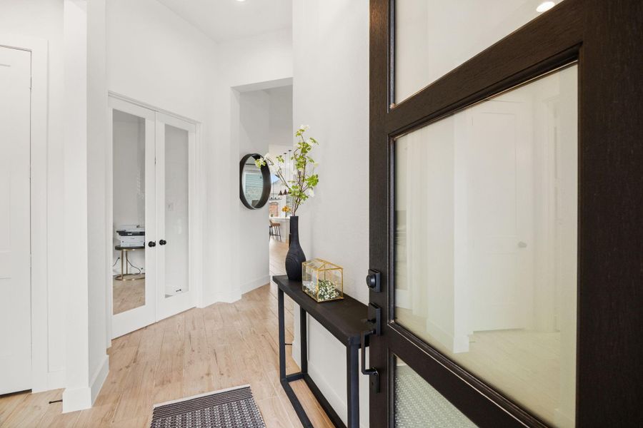 Step inside to a bright foyer with high ceilings, wood-look flooring, and a sleek glass-paneled entry door that brings in natural light.