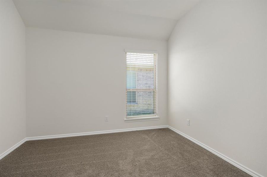 Carpeted empty room with vaulted ceiling and baseboards Carpeted empty room with vaulted ceiling and baseboards