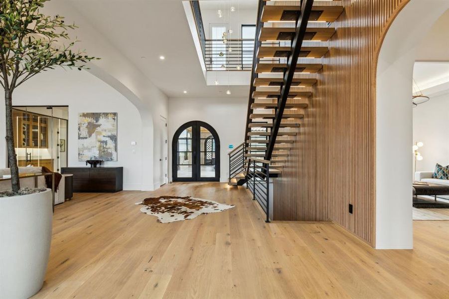 Foyer featuring arched walkways, a high ceiling, light wood-style flooring, recessed lighting, and stairs Foyer featuring arched walkways, a high ceiling, light wood-style flooring, recessed lighting, and stairs