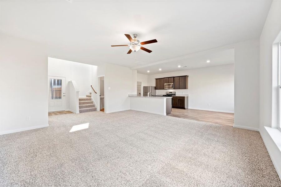 Unfurnished living room with light carpet and ceiling fan