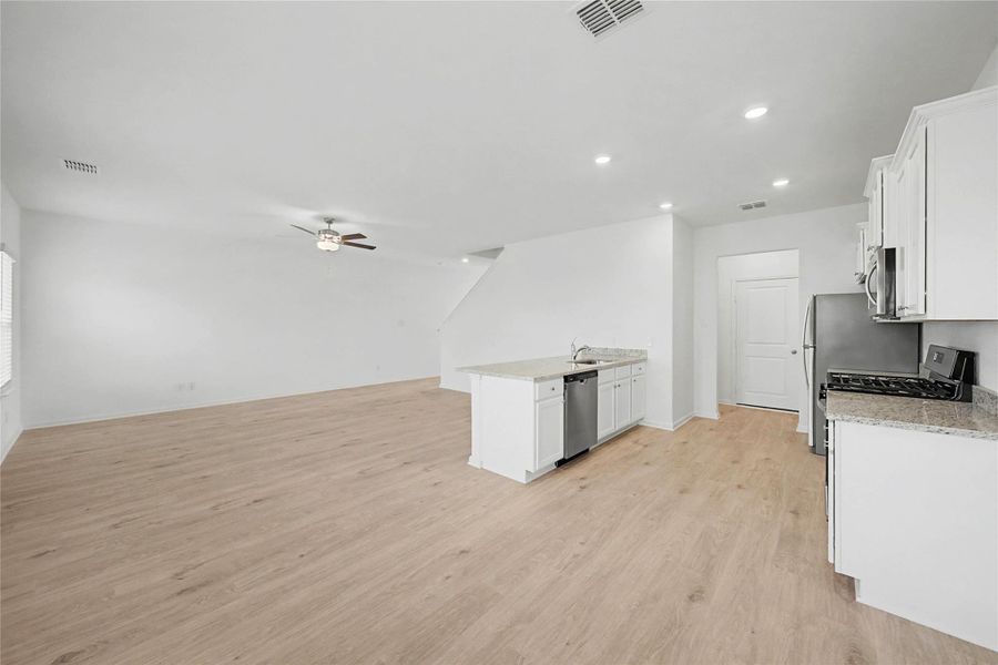 Kitchen featuring a peninsula, white cabinetry, open floor plan, light wood finished floors, and recessed lighting