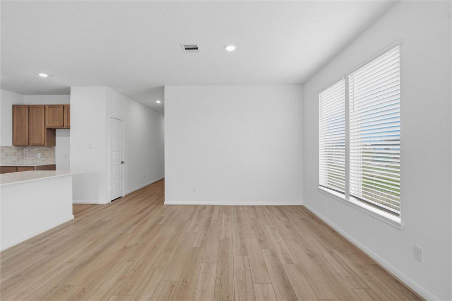 Start your day with a warm cup of coffee and quality time in this charming dining area! Highlights include large windows with blinds, custom neutral paint, vinyl plank flooring, and high ceilings with recessed lighting.