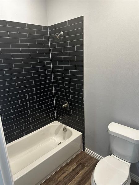 Hall Bathroom featuring Tile Surround Tub/Shower; toilet, wood-type flooring, and tiled shower / bath