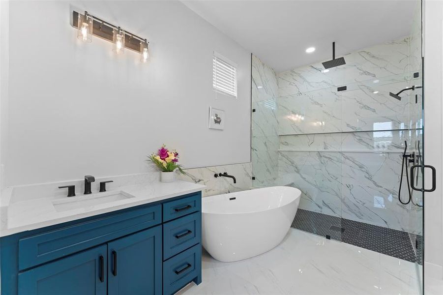 Full bath featuring a marble finish shower, a freestanding tub, vanity, light marble finish flooring, and tile walls Full bath featuring a marble finish shower, a freestanding tub, vanity, light marble finish flooring, and tile walls
