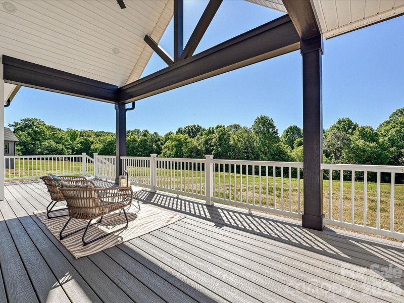 Expansive covered back deck with vaulted ceilings and peaceful wooded views creates the perfect setting for relaxing or entertaining outdoors year-round.