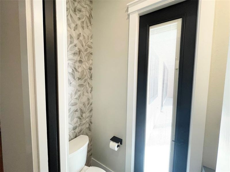 Powder room with back patio access features tile wall and cabinet sink.