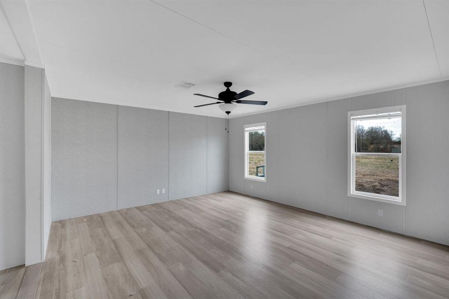Empty room with a decorative wall, light wood finished floors, and ceiling fan