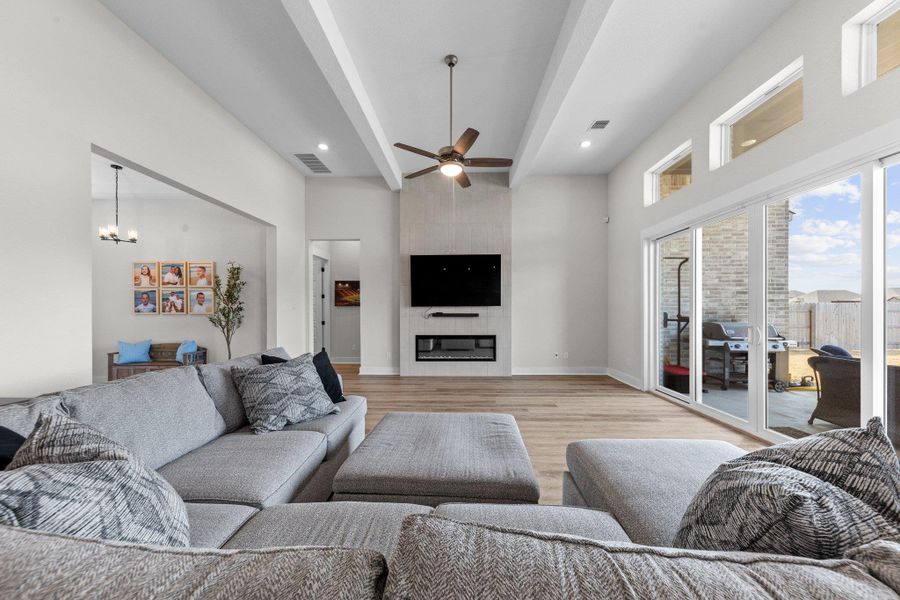 Living area with a large fireplace, baseboards, visible vents, light wood-style floors, and ceiling fan