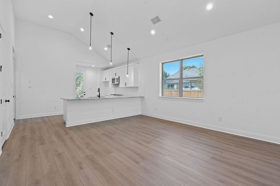 Unfurnished living room with light wood-style flooring, recessed lighting, and high vaulted ceiling