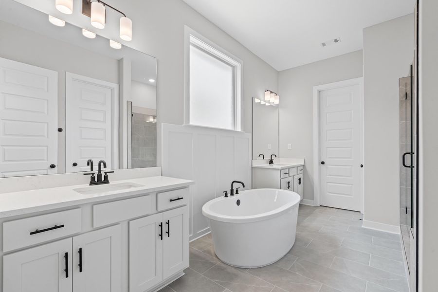 Full bath with a shower stall, two vanities, a freestanding bath, and light tile patterned floors Full bath with a shower stall, two vanities, a freestanding bath, and light tile patterned floors