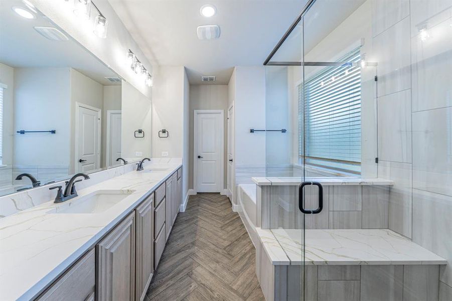 Bathroom featuring an extended dual vanity with undermount sinks and dark fixtures, an expansive mirror, and overhead lighting