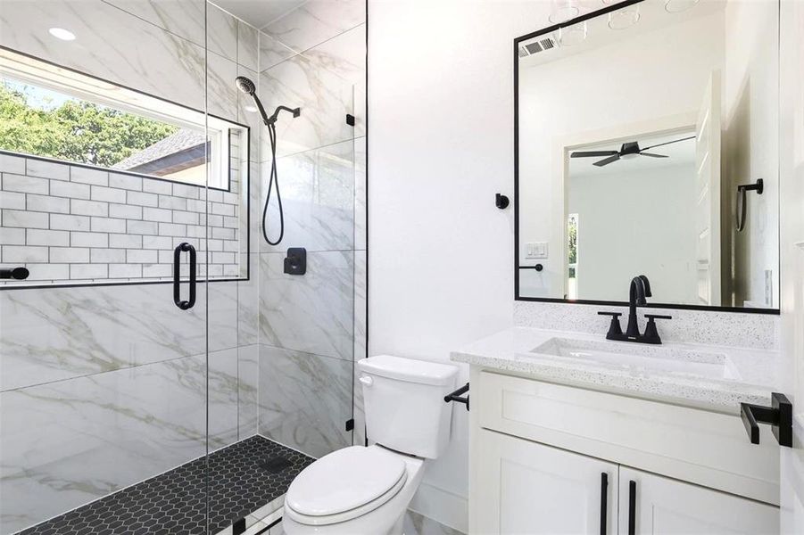 Modern bathroom featuring a walk-in shower with clear glass enclosure and matte black fixtures