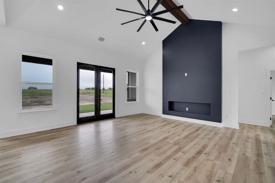 Unfurnished living room featuring high vaulted ceiling, light wood-type flooring, french doors, and beamed ceiling