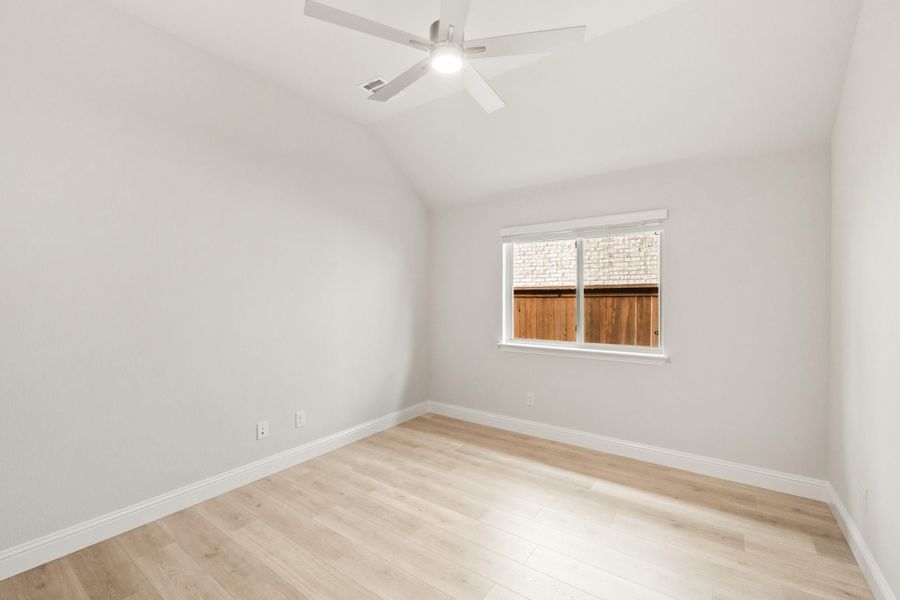 Empty bedroom with vaulted ceiling, ceiling fan, light wood floors, and single window Empty bedroom with vaulted ceiling, ceiling fan, light wood floors, and single window