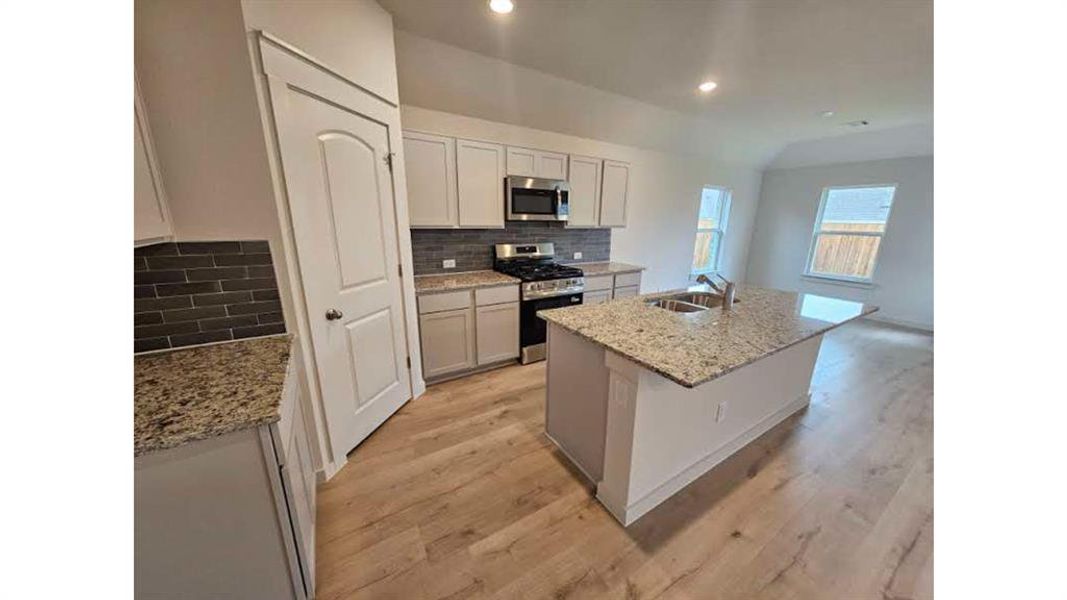 Contemporary kitchen featuring an island with a double basin sink and extended countertop seating