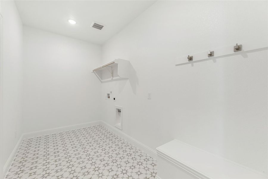 Laundry room with patterned tile floor, wall hooks, built-in shelf, and washer and dryer hookups