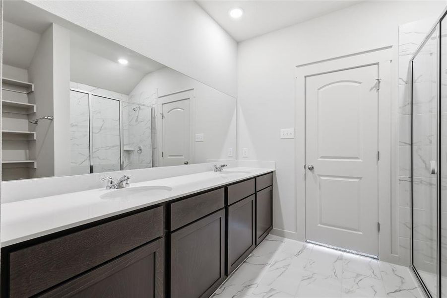 Bathroom with light marble finish floors, double vanity, a marble finish shower, and a closet