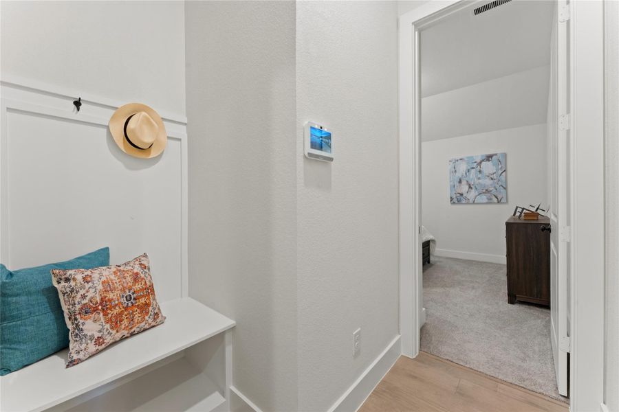 Hallway entry featuring built-in bench seating with paneling and coat hooks