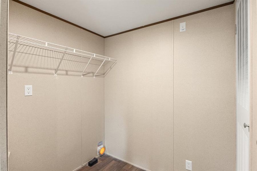 Utility area featuring wire shelving, wood-finish flooring, a louvered door, and wall outlets