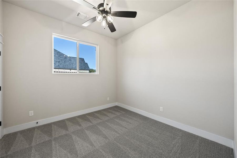 Unfurnished room featuring ceiling fan and dark colored carpet