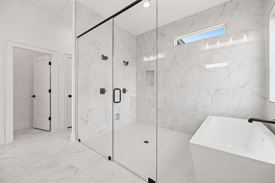Bathroom featuring a soaking tub, marble finish floor, a stall shower, and a sink