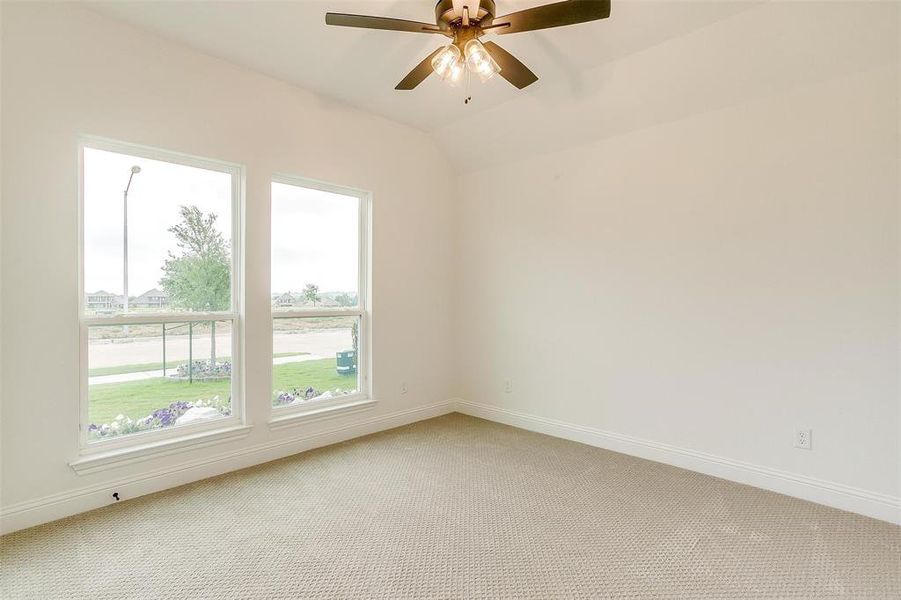 Carpeted empty room with lofted ceiling and ceiling fan