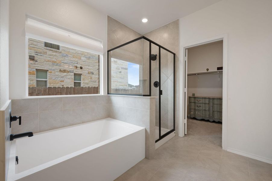 Full bathroom with a bath, a stall shower, a walk in closet, and light tile patterned floors