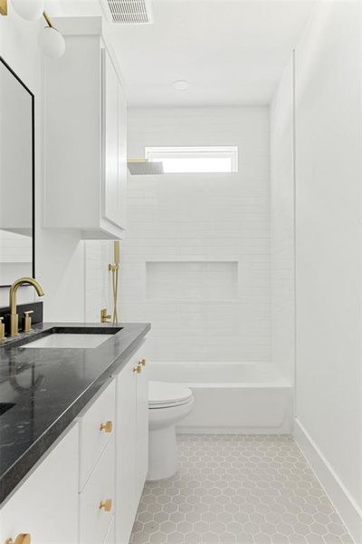 Full bathroom featuring tile flooring, toilet, vanity with extensive cabinet space, and tiled shower / bath combo