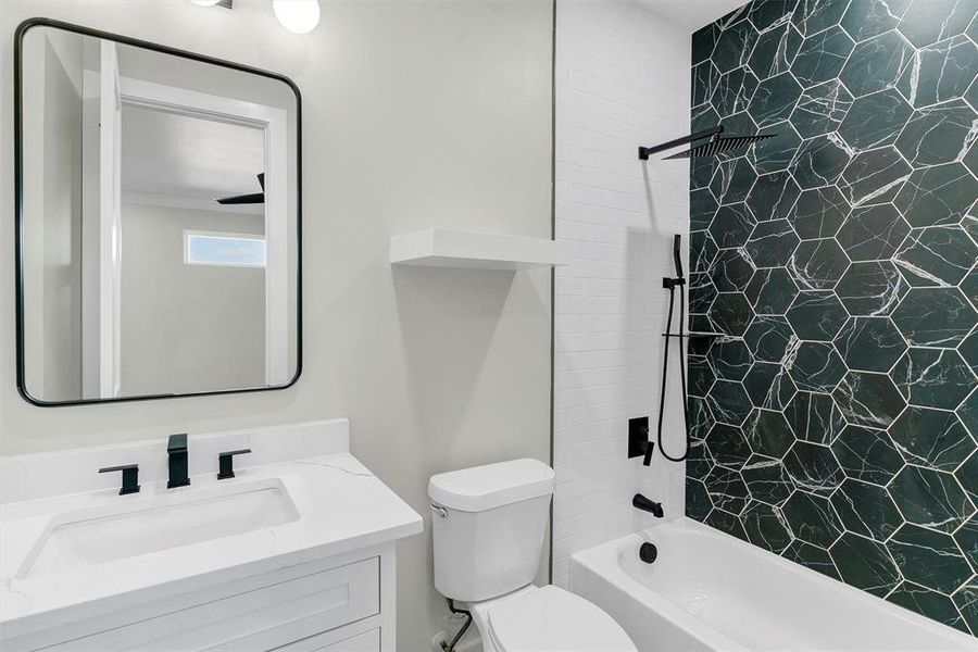 Full bathroom featuring vanity, tiled shower / bath combo, and toilet