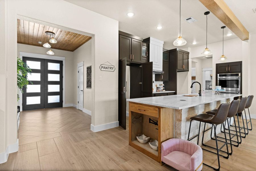 Kitchen featuring oven, baseboards, a sink, wood ceiling, and a spacious island Kitchen featuring oven, baseboards, a sink, wood ceiling, and a spacious island