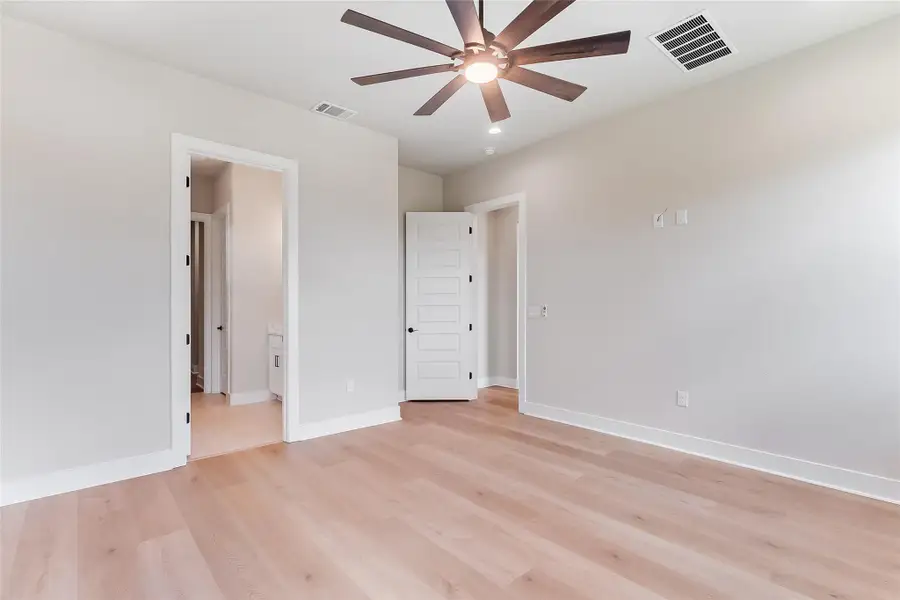 Unfurnished bedroom featuring light wood finished floors, ceiling fan, and ensuite bathroom