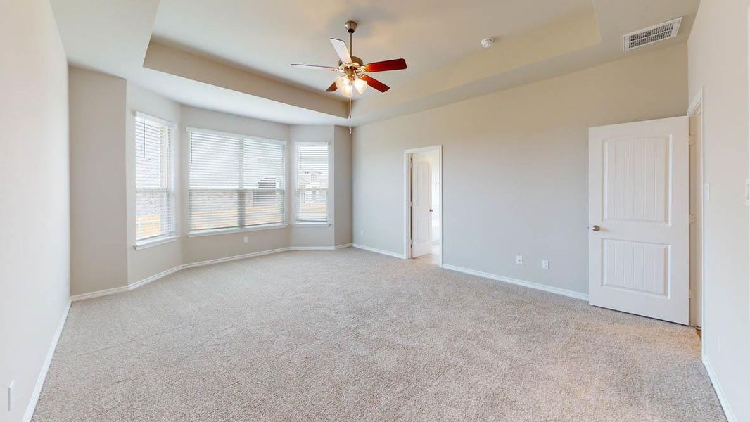 Unfurnished bedroom with a raised ceiling, ceiling fan, and light carpet