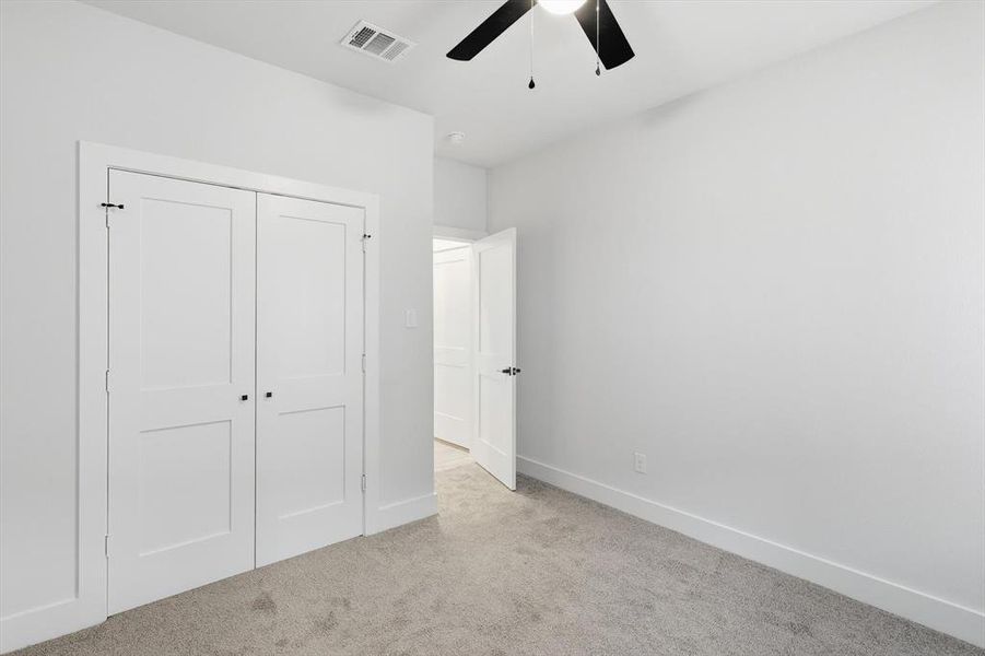 Unfurnished bedroom featuring light colored carpet, a closet, and ceiling fan