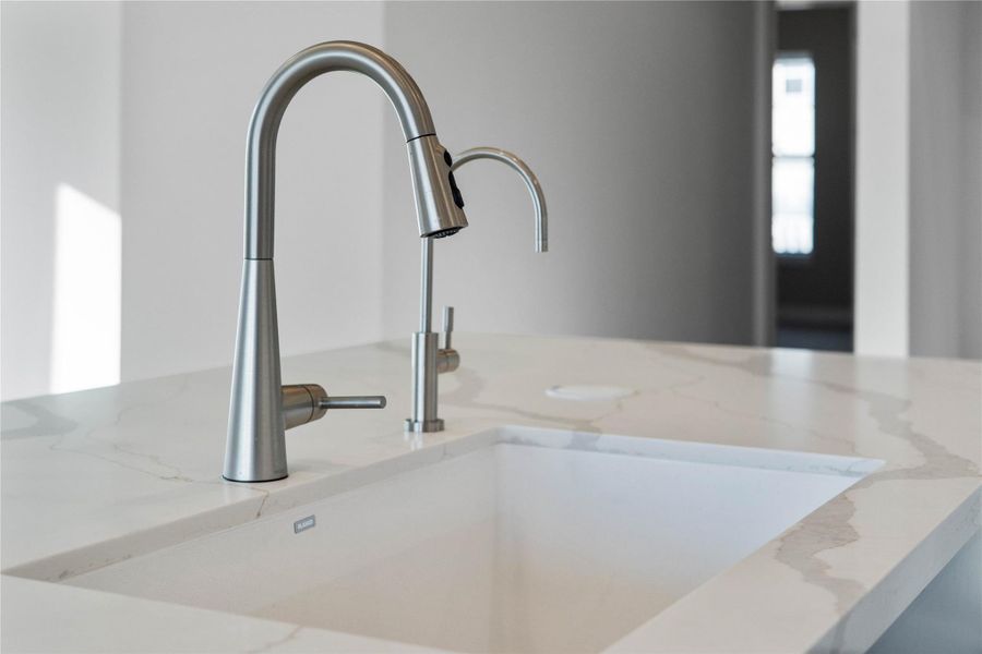 The modern undermount sink is perfectly in the kitchen island, offering views the open-concept living space.