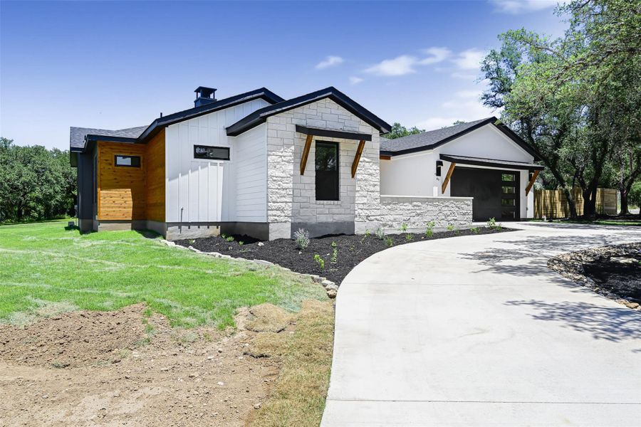 Modern farmhouse with concrete driveway, an attached garage, board and batten siding, and stone siding