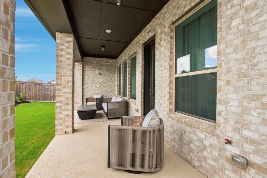Charming covered patio with elegant brickwork, cozy seating, and a view of the lush green lawn—ideal for outdoor relaxation and entertaining.