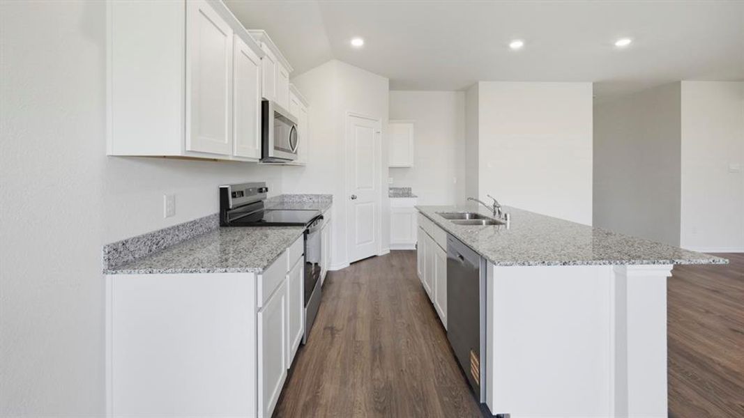 Kitchen featuring stainless steel appliances, light stone countertops, white cabinets, dark wood-type flooring, and recessed lighting