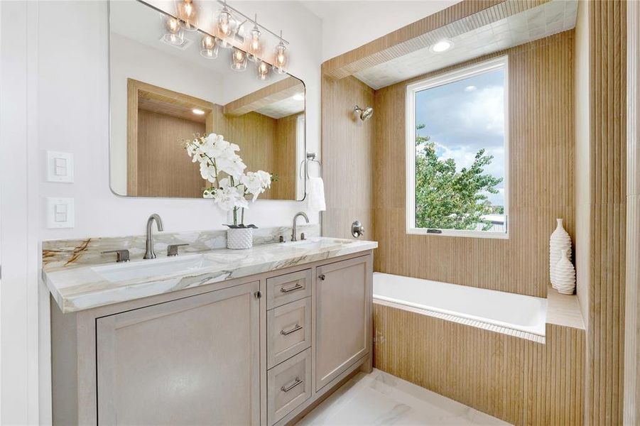 Another view of the vanity with custom cabinets and the soaking tub with a shower head.