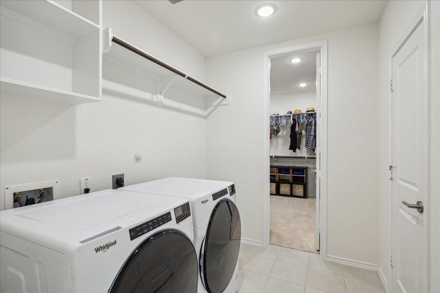 Laundry/utility area with two access points, one being the primary closet, complete with shelves and hanging racks.
